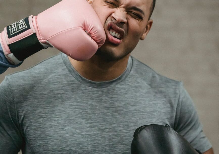 unrecognizable boxer hitting young ethnic sportsman during training